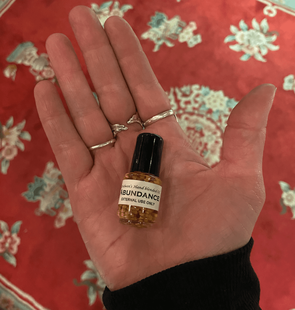 a tiny bottle of Abundance Oil on the palm of a person